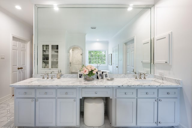 bathroom featuring double vanity, crown molding, baseboards, and recessed lighting