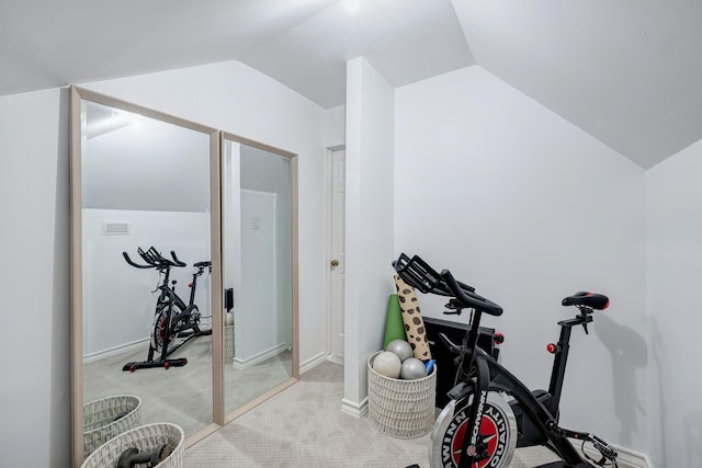 exercise room with lofted ceiling, light colored carpet, and baseboards