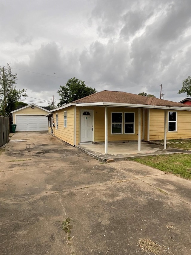 view of front of property featuring a detached garage, driveway, covered porch, and an outdoor structure
