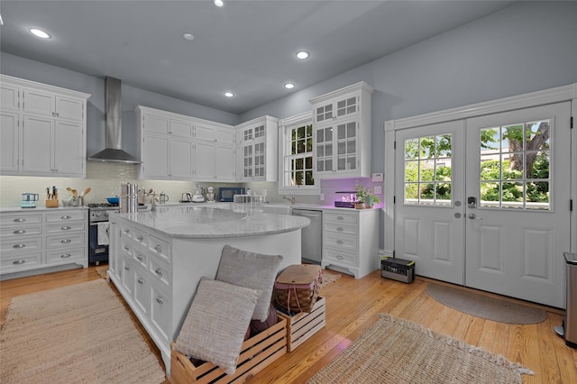 1818 Decatur St, Houston, TX 77007 - kitchen with wall chimney range hood, stainless steel appliances, white cabinetry, a kitchen island, and backsplash