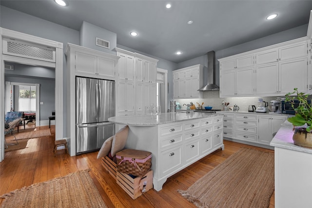 1818 Decatur St, Houston, TX 77007 - kitchen with freestanding refrigerator, wall chimney exhaust hood, white cabinetry, a kitchen island with sink, and recessed lighting