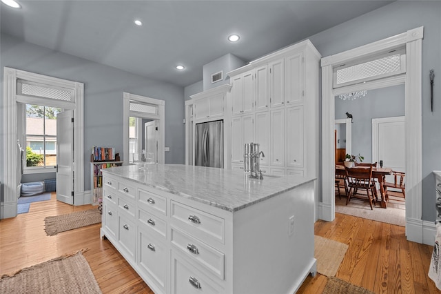 1818 Decatur St, Houston, TX 77007 - kitchen with freestanding refrigerator, a sink, white cabinets, an island with sink, and light stone counters