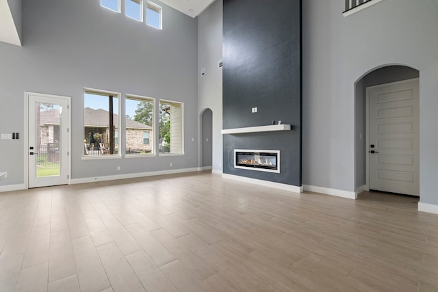 250 Hampton Glen Rd, Montgomery, TX 77356 - unfurnished living room featuring a high ceiling, arched walkways, baseboards, and wood finished floors