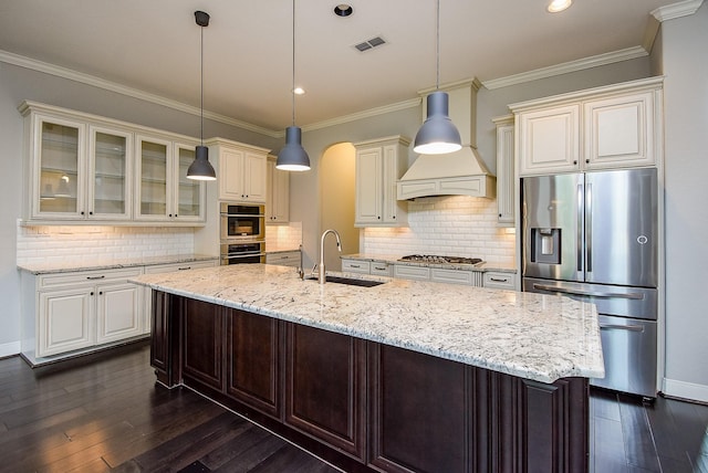 kitchen with appliances with stainless steel finishes, a sink, glass insert cabinets, dark wood-style flooring, and light stone countertops