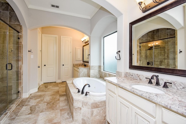 bathroom featuring a stall shower, a bath, ornamental molding, and two vanities
