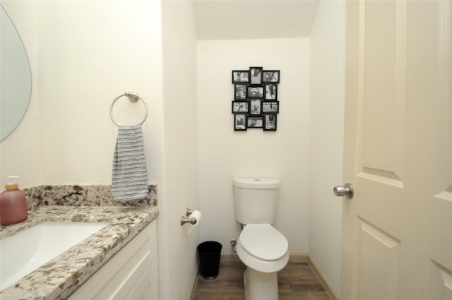 bathroom with vanity, toilet, wood finished floors, and baseboards