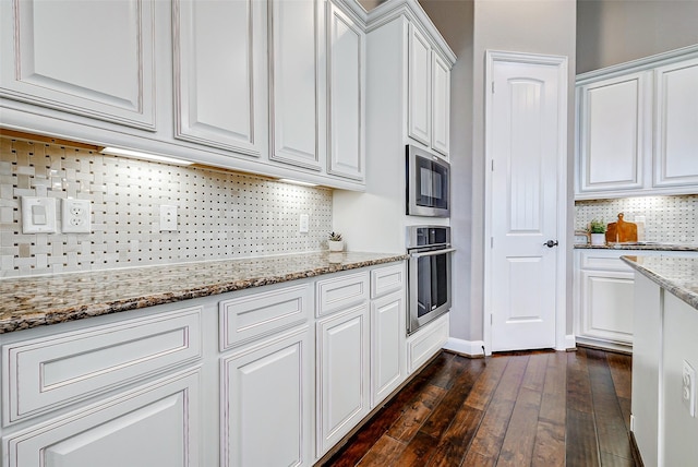 6315 Asbury Brook Ct, Katy, TX 77493 - kitchen featuring appliances with stainless steel finishes, white cabinets, dark wood finished floors, decorative backsplash, and light stone countertops