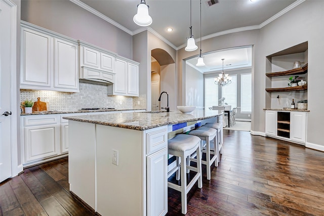 6315 Asbury Brook Ct, Katy, TX 77493 - kitchen featuring arched walkways, dark wood-style floors, a kitchen breakfast bar, ornamental molding, and white cabinets