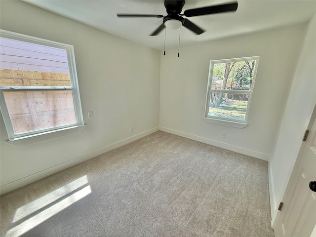 carpeted spare room featuring ceiling fan and baseboards