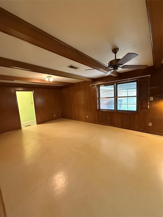 spare room with beamed ceiling, wooden walls, and a ceiling fan