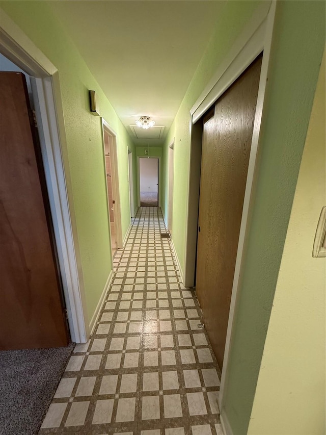 hallway featuring attic access and light flooring