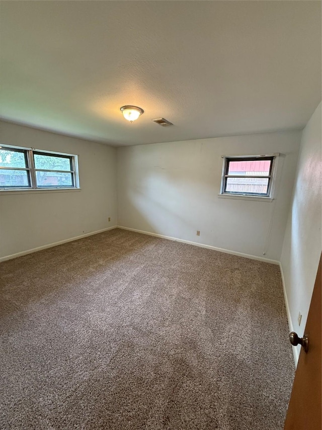 spare room with carpet flooring, baseboards, and a textured ceiling