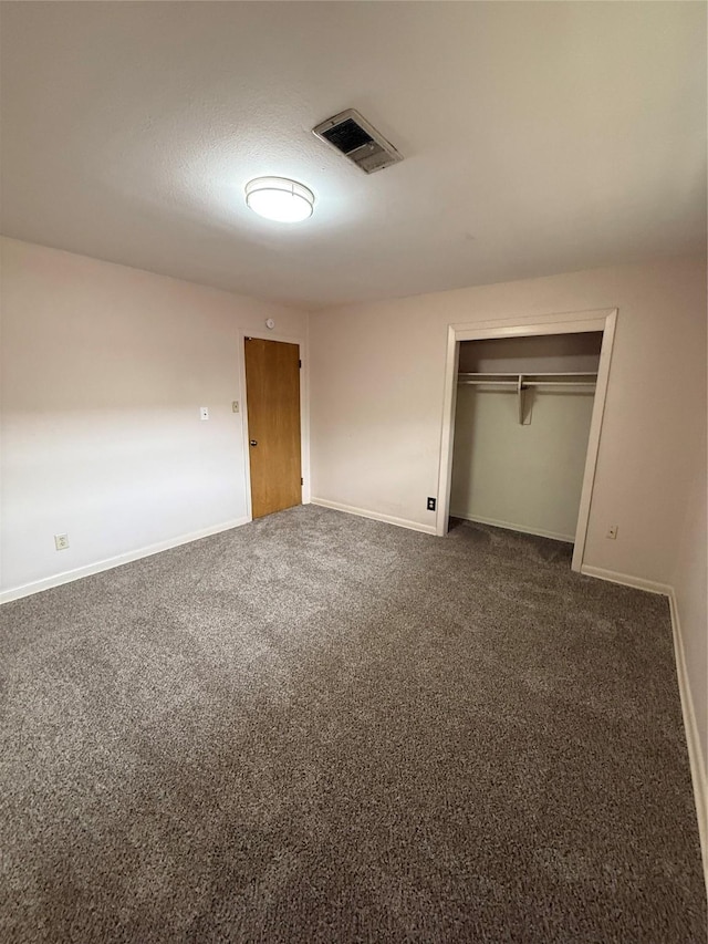 unfurnished bedroom featuring dark colored carpet, baseboards, and a closet