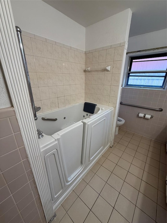 full bath with tile walls, tile patterned floors, a tub with jets, and toilet