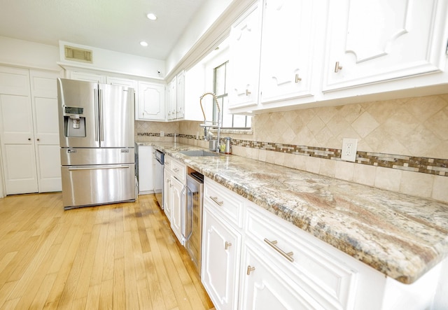 11810 Braesridge Dr, Houston, TX 77071 - kitchen with appliances with stainless steel finishes, a sink, white cabinets, light wood-type flooring, and backsplash