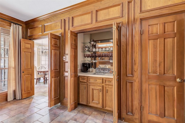 indoor wet bar with healthy amount of natural light, wood walls, and light stone finish floors