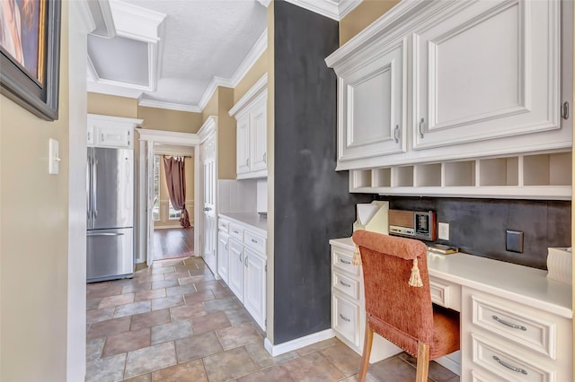 home office with built in desk, stone finish flooring, crown molding, and baseboards