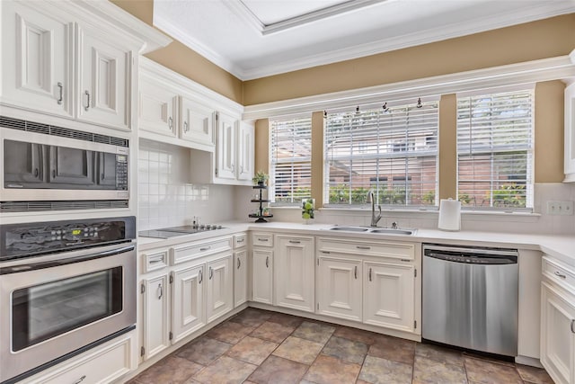 kitchen with appliances with stainless steel finishes, a sink, plenty of natural light, white cabinets, and crown molding