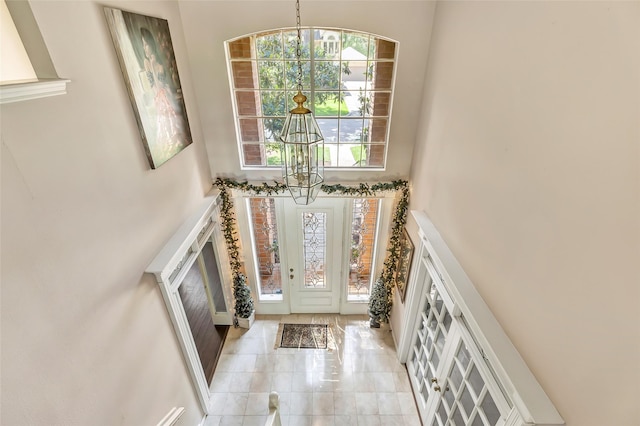 foyer entrance with a towering ceiling, a chandelier, and light tile patterned floors
