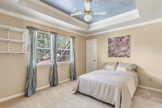 carpeted bedroom featuring a tray ceiling, crown molding, baseboards, and ceiling fan
