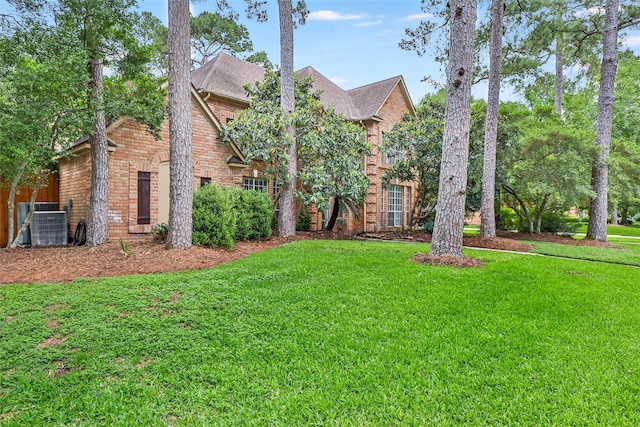view of front of property with a front yard, brick siding, and central air condition unit