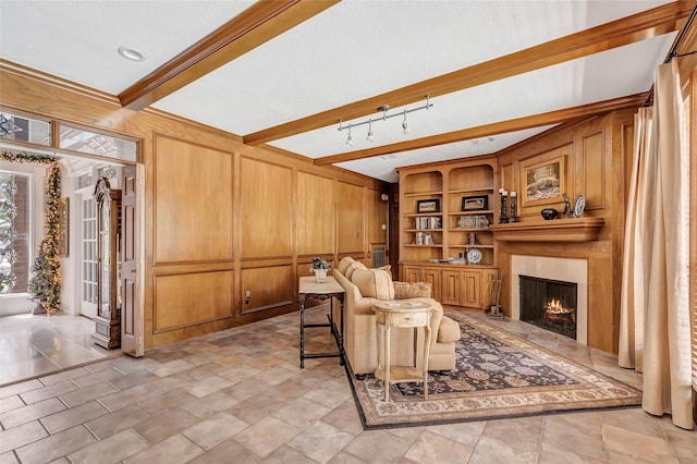 living area featuring a large fireplace, wooden walls, built in shelves, and beam ceiling