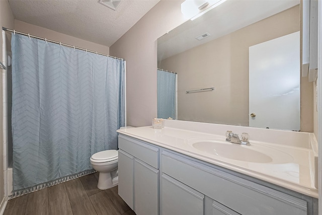 bathroom featuring wood finished floors, toilet, vanity, a textured ceiling, and shower / tub combo