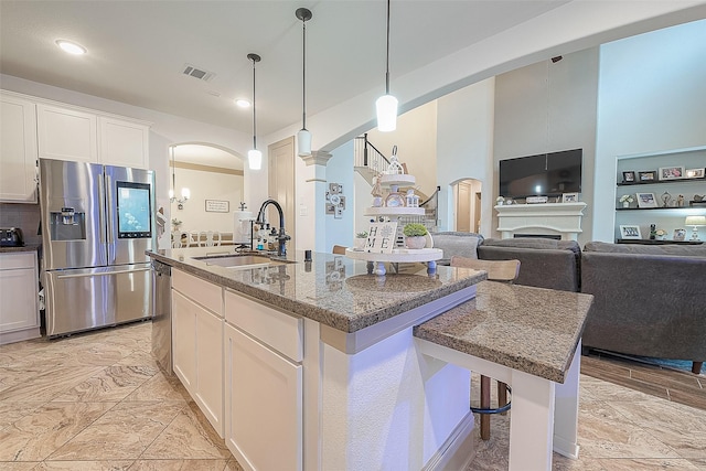 3911 Avalon Ridge Dr, Spring, TX 77386 - kitchen featuring stainless steel appliances, a sink, arched walkways, a kitchen island with sink, and white cabinetry