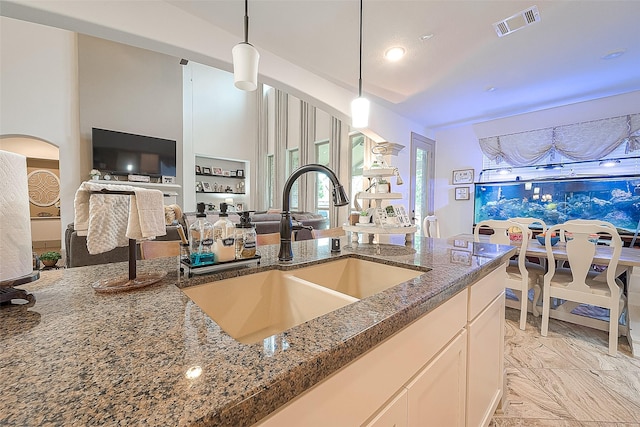 3911 Avalon Ridge Dr, Spring, TX 77386 - kitchen featuring a sink, dark stone counters, pendant lighting, open floor plan, and white cabinets