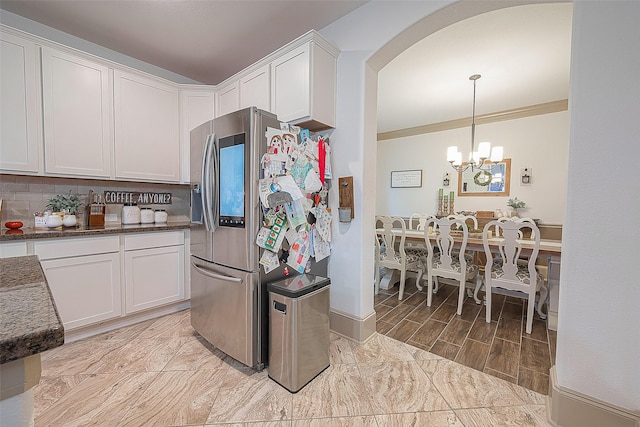 3911 Avalon Ridge Dr, Spring, TX 77386 - kitchen featuring stainless steel refrigerator with ice dispenser, arched walkways, a chandelier, white cabinetry, and dark stone counters
