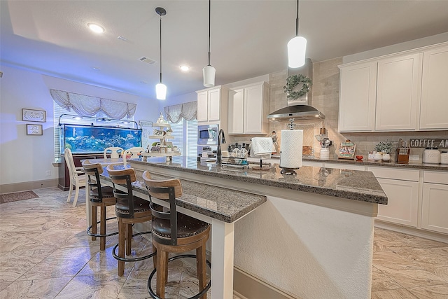 3911 Avalon Ridge Dr, Spring, TX 77386 - kitchen with stainless steel microwave, an island with sink, a sink, dark stone counters, and a breakfast bar area