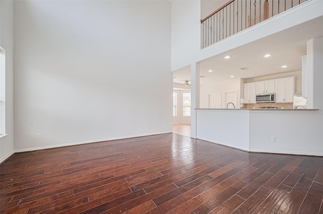 4142 Regal Stone Ln, Sugar Land, TX 77479 - unfurnished living room featuring dark wood-style flooring, a towering ceiling, and baseboards