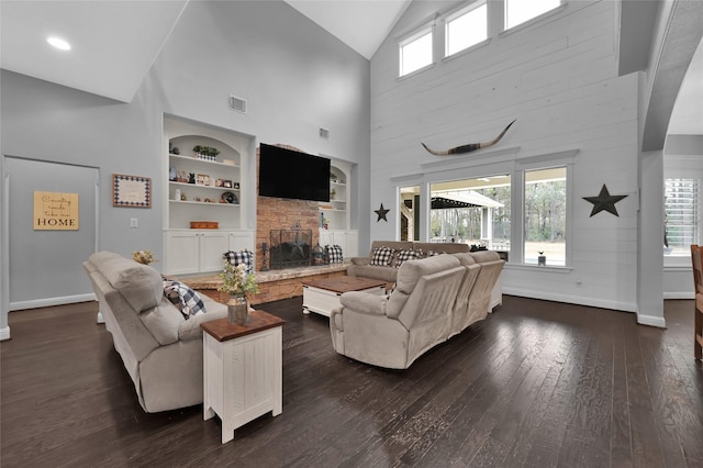 3315 Spring Branch Rd, Montgomery, TX 77316 - living room featuring a stone fireplace, built in shelves, baseboards, dark wood-style flooring, and high vaulted ceiling
