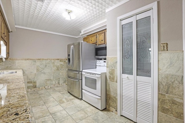 13519 Montgomery Rd, Santa Fe, TX 77510 - kitchen featuring appliances with stainless steel finishes, tile walls, brown cabinets, crown molding, and a sink