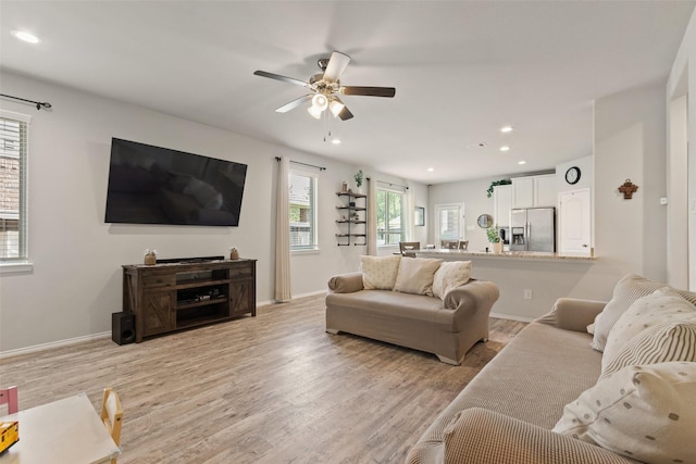 living area with recessed lighting, light wood-style floors, a ceiling fan, and baseboards