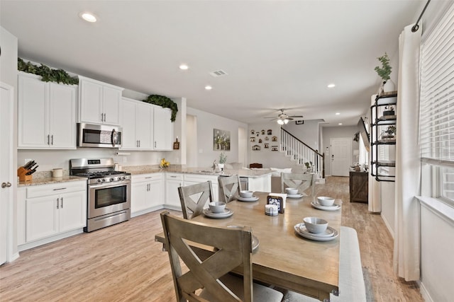kitchen featuring appliances with stainless steel finishes, a peninsula, light wood-style flooring, white cabinets, and recessed lighting