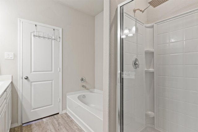 bathroom featuring a stall shower, vanity, a garden tub, and wood finished floors