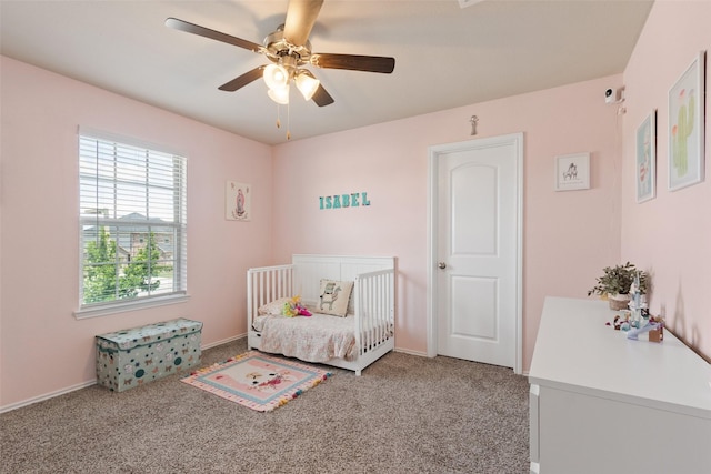 bedroom with a crib, carpet, ceiling fan, and baseboards