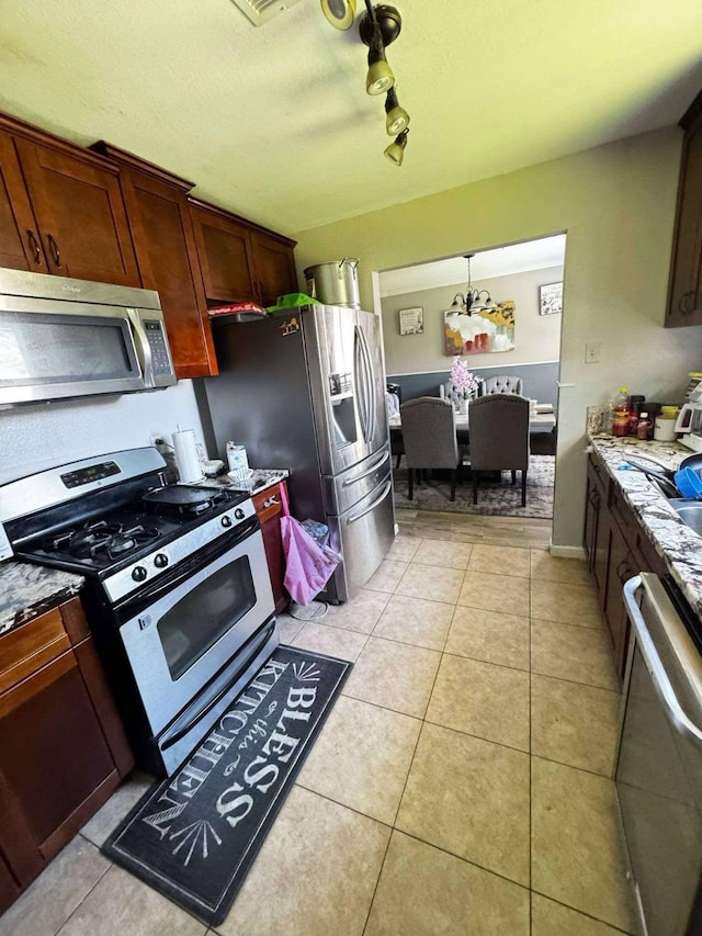 8206 Claiborne St, Houston, TX 77078 - kitchen with stainless steel appliances, light tile patterned floors, stone countertops, and track lighting