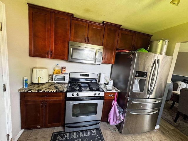 8206 Claiborne St, Houston, TX 77078 - kitchen with appliances with stainless steel finishes, dark stone countertops, reddish brown cabinets, light tile patterned floors, and lofted ceiling