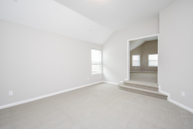 carpeted empty room with lofted ceiling and baseboards