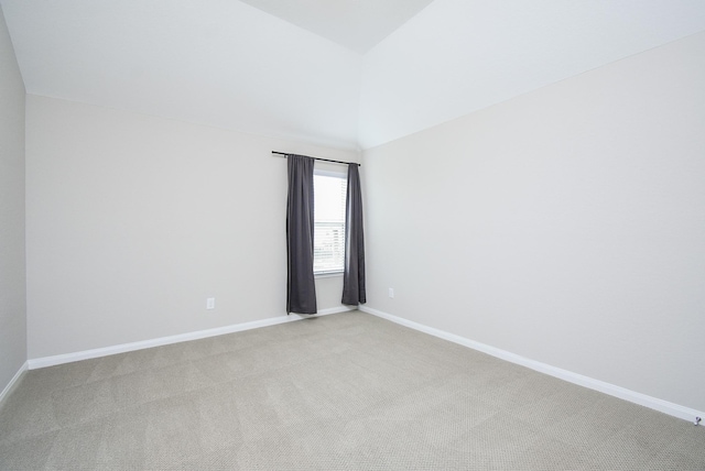 unfurnished room with light carpet, vaulted ceiling, and baseboards