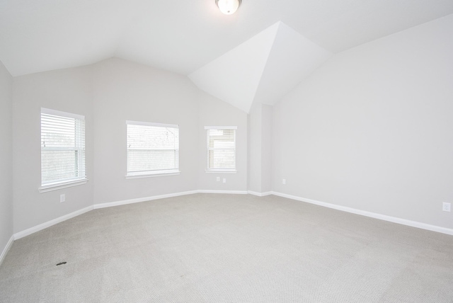 carpeted empty room with lofted ceiling and baseboards