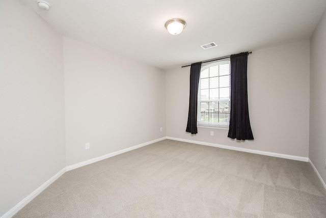 spare room with light colored carpet, baseboards, and a smoke detector