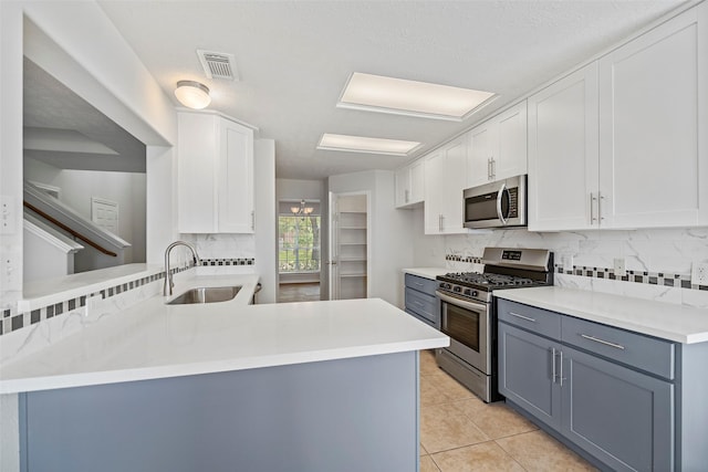 kitchen featuring stainless steel appliances, a sink, backsplash, light countertops, and white cabinets