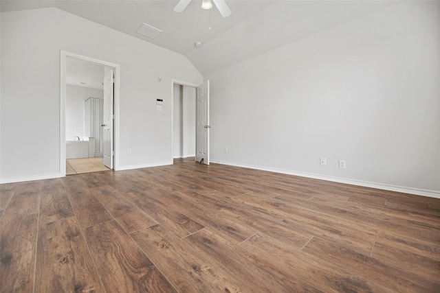 unfurnished bedroom featuring lofted ceiling, wood finished floors, ensuite bathroom, ceiling fan, and baseboards