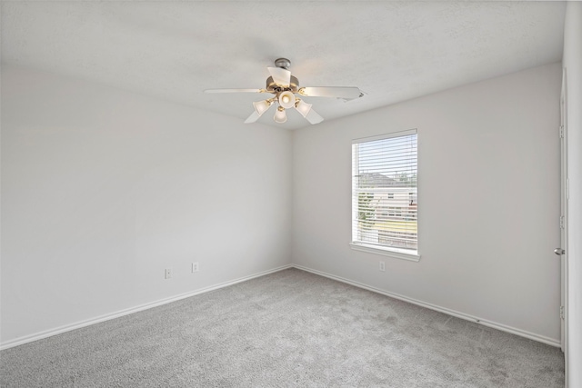 carpeted empty room with a ceiling fan and baseboards