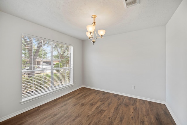 empty room with a chandelier, baseboards, dark wood-style flooring, and a textured ceiling