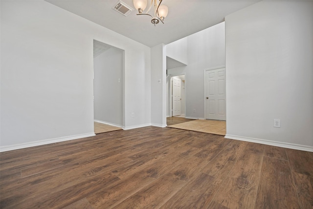empty room featuring a chandelier, baseboards, and wood finished floors