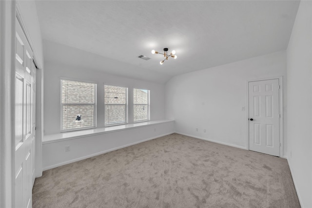carpeted empty room with a chandelier, baseboards, and lofted ceiling